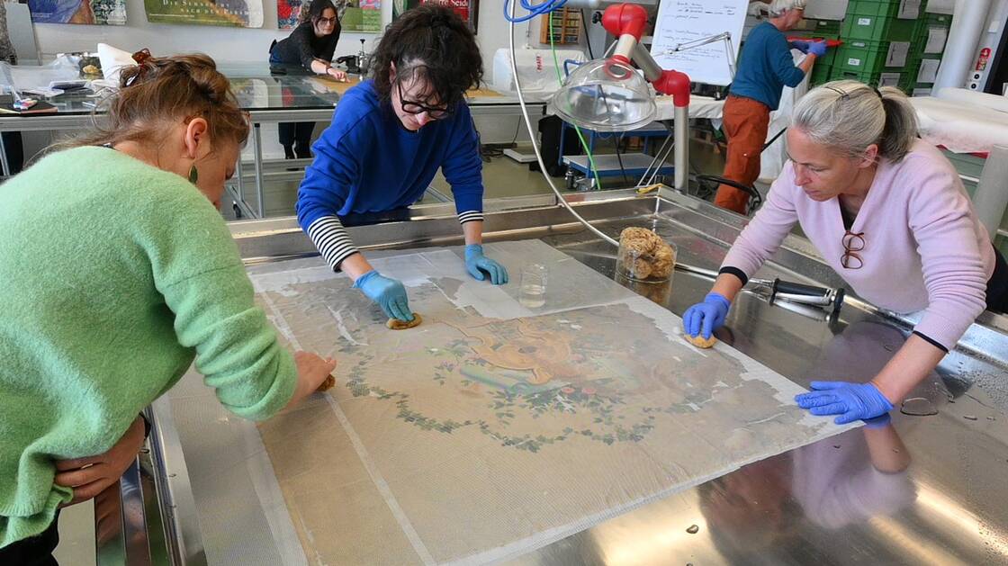 Wässrige Reinigung eines Fahnenblattes, welches zwischen zwei Lagen Tüll geschützt wird.