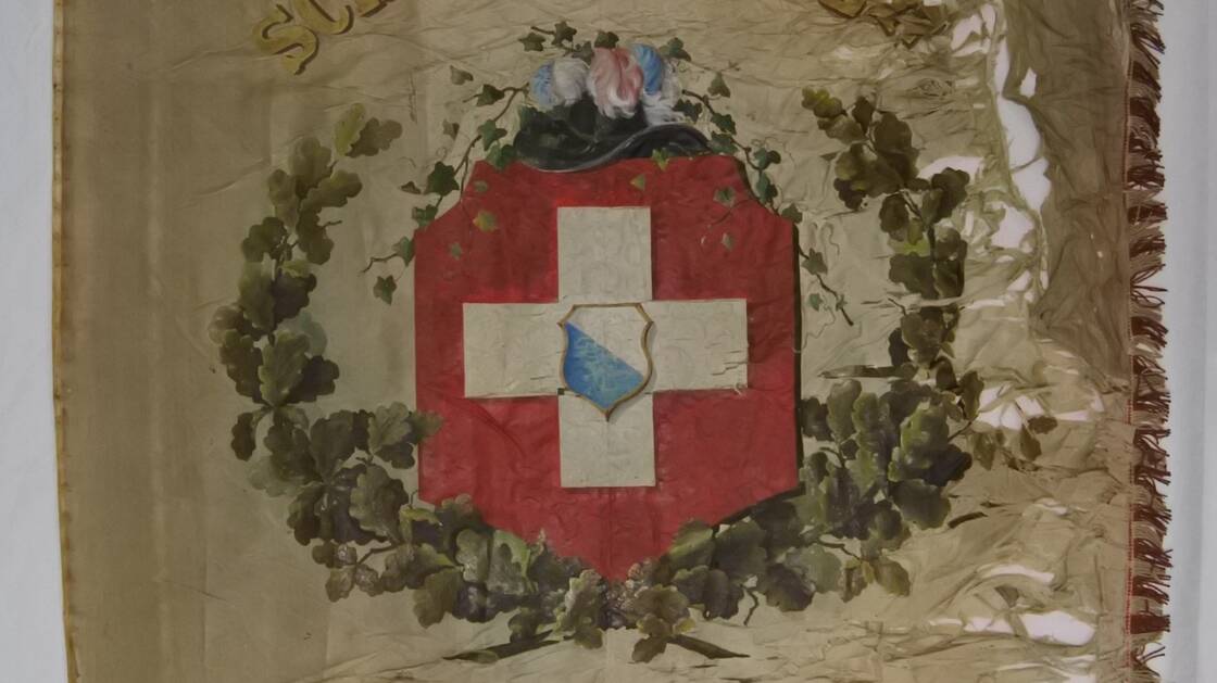 Das Bild zeigt eine Fahne eines Schützenvereins, die an mehreren Stellen zerrissen ist und einige Löcher hat. | © Schweizerisches Nationalmuseum