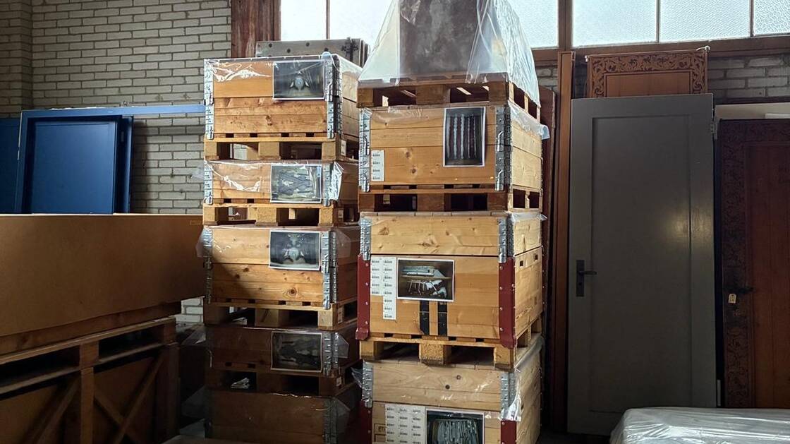 Foto aus dem Alten Zeughaus vom Sammlungszentrum, das aufeinander gestapelte Paletten und in Plastik verpackte Objekte zeigt, die für den Umzug in die neuen Depoträumlichkeiten vorbereitet wurden.